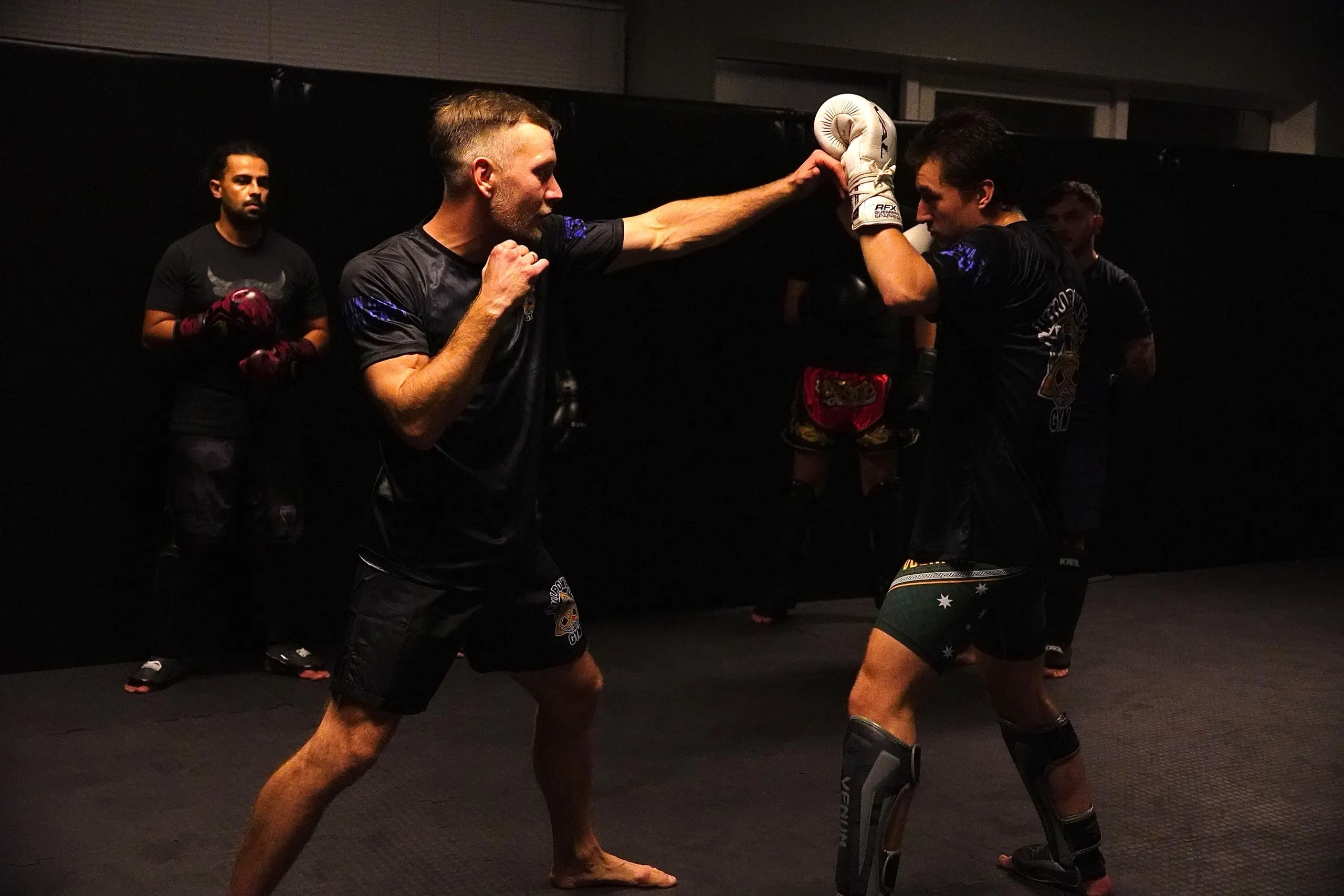 Twee leden trainen stoten op de pads in de zaal van Willpower Gym